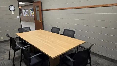 Study room with rectangle table and 6 black chairs.