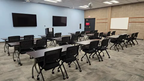 Auditorium with tables and chairs set up classroom style.