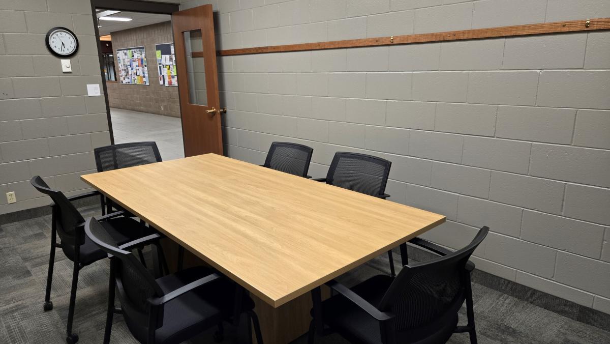 Study room with rectangle table and 6 black chairs.